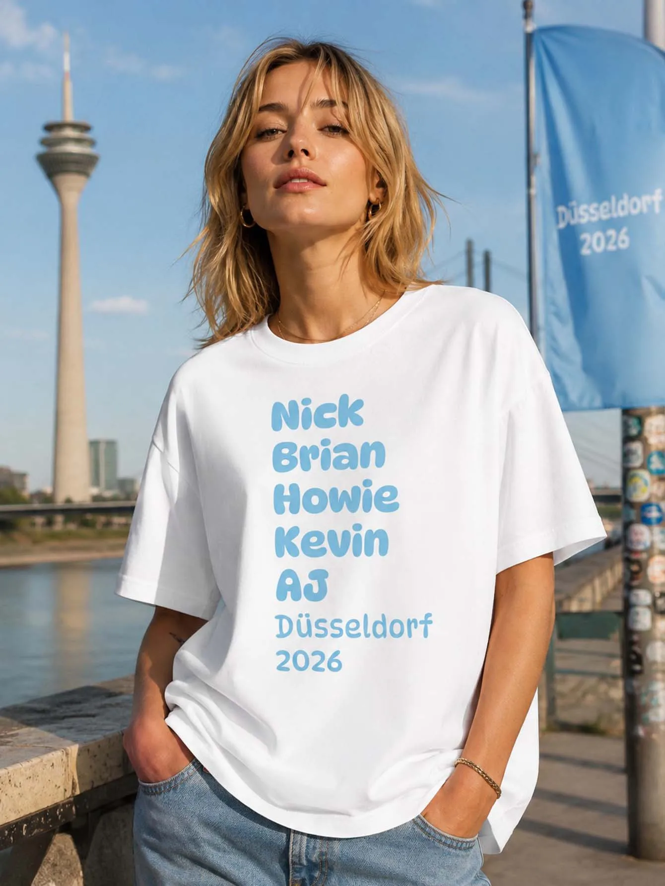 T-shirt graphique blanc avec les noms de Nick, Brian, Howie, Kevin, AJ et le texte Düsseldorf 2026 en typographie arrondie bleu doux, T-shirt imprimé pour femme