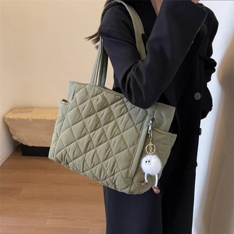 Schwarze Handtasche mit großem Fassungsvermögen und quadratischem Muster, strapazierfähiges Steppmaterial, mehrere Taschen für einfache Aufbewahrung und niedlicher Plüschanhänger