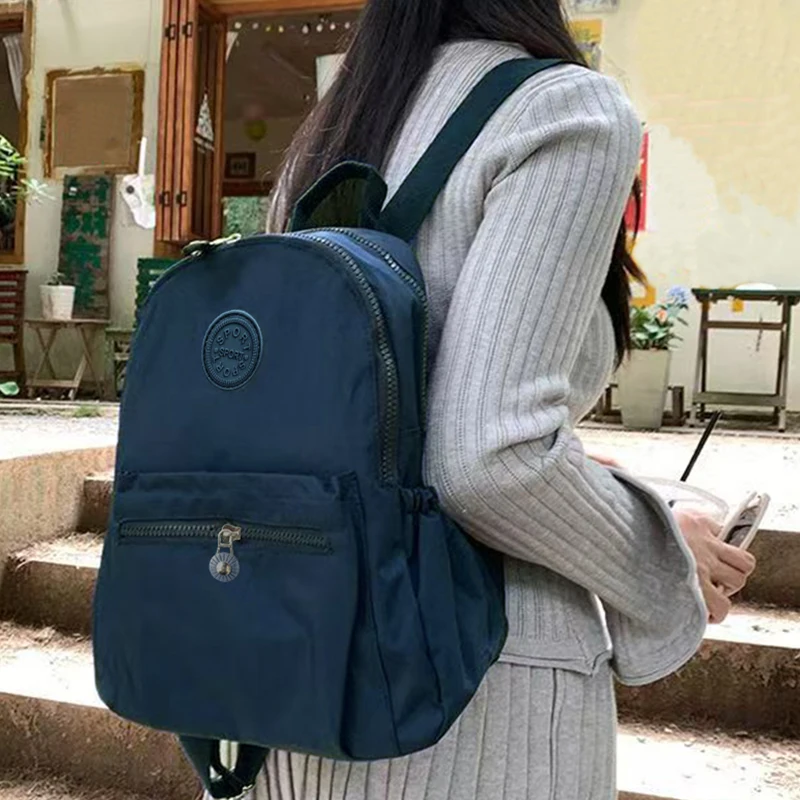 حقيبة ظهر بتصميم محايد للرجال والنساء، مناسبة للسفر والتصوير الفوتوغرافي مصنوعة من مادة النايلون، مع تصميم شعار دائري.