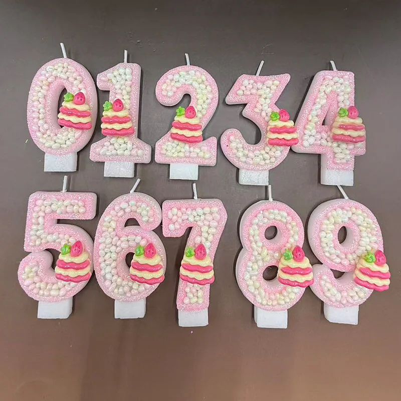 Pink pearl strawberry cupcakes decorated with birthday number candles, birthday commemorative candles, and party small gifts