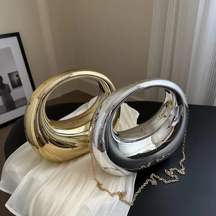 

Трубач носит сумку, которую можно носить через плечо, в форме полумесяца — это блестящая вечерняя сумка, подходящая для балов и нарядов с пайетками.