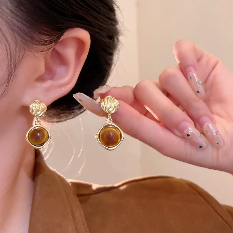 Golden earrings featuring tiger eye stones, with an extremely bold design. Suitable for women to wear in autumn and winter, for