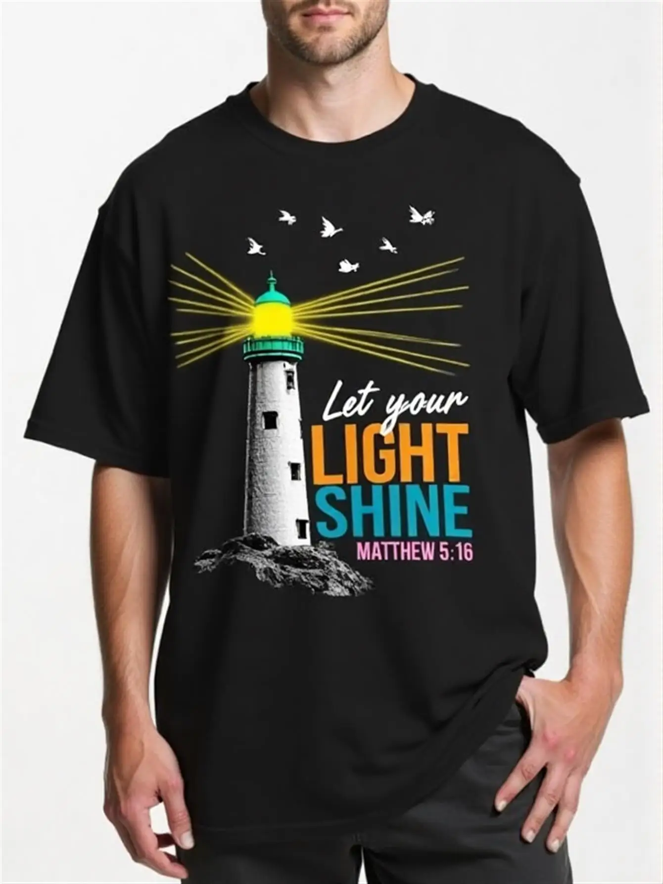 Camiseta de Corte Holgado con Versículo Bíblico: La Fe Cristiana Deja que Tu Luz Brille - Mateo 5:16, Prenda Religiosa, Suave y Transpirable, Ropa Cristiana Unisex - Patrón de Faro Negro con Rayos Coloridos - Lavable a Máquina, para Uso Diario