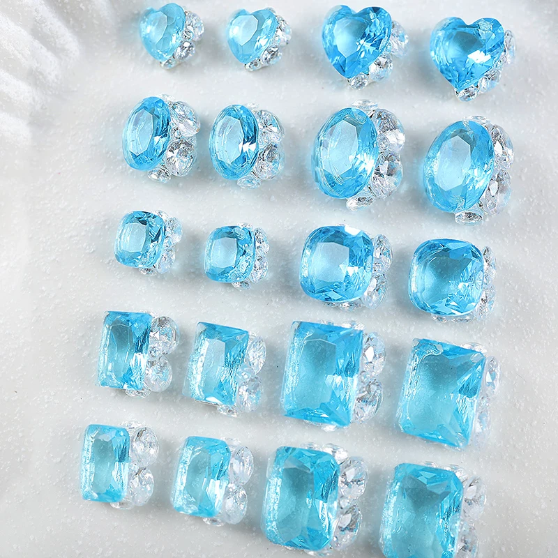 เครื่องประดับเล็บสีฟ้าน้ำแข็งระดับพรีเมียม 20 ชิ้นพร้อมคิวบิกเซอร์โคเนียที่วางอยู่ด้วยมือ โดดเด่นด้วยรูปทรงเรขาคณิตแบบซ้อนและรูปหัวใจ