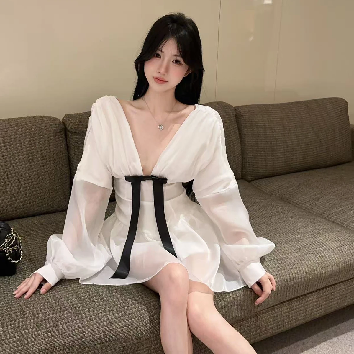 เดรสสั้นสีขาวแบบเซ็กซี่สไตล์ฝรั่งเศส คอวีลึก แต่งโบว์ แขนยาวทรงโคมไฟ ผ้าบาง โชว์เอวเข้ารูป ทรงเอไลน์ เหมาะสำหรับงานวันเกิด