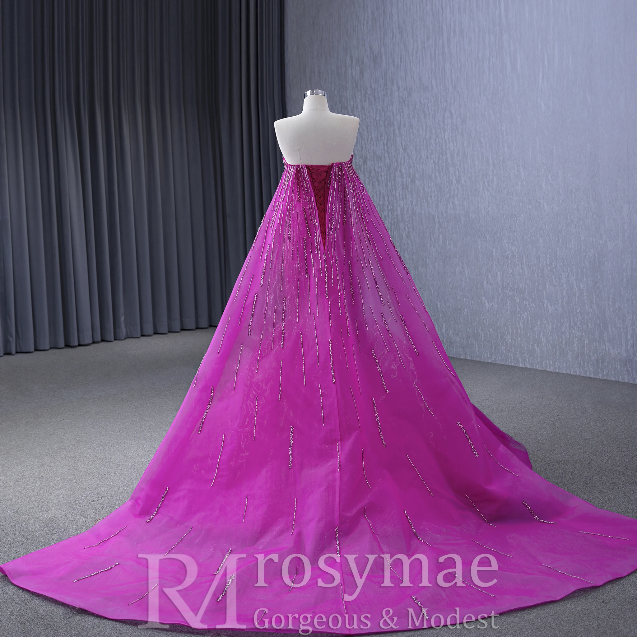 Suknia wieczorowa Rosymae, ekskluzywna, fuksjowa, zdobiona koralikami, bez ramiączek, o kroju trąbki, z peleryną na plecach, z trenem typu court, idealna na formalne okazje.