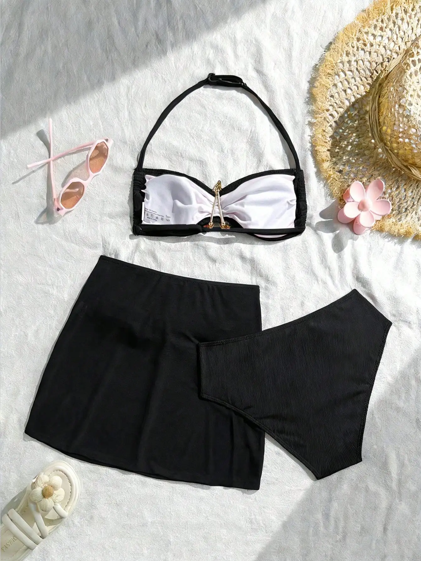 

Черный комплект из трех предметов: топ-бандо с золотой застежкой, ребристые плавки-треугольники и съемная юбка-накидка.