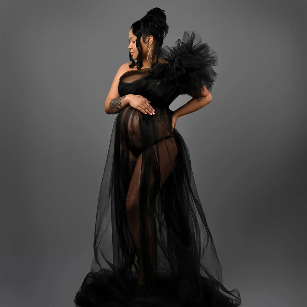 Coloris noir La robe de grossesse en tulle noir, la manche ballon froncée formant un large volant sur l'épaule.