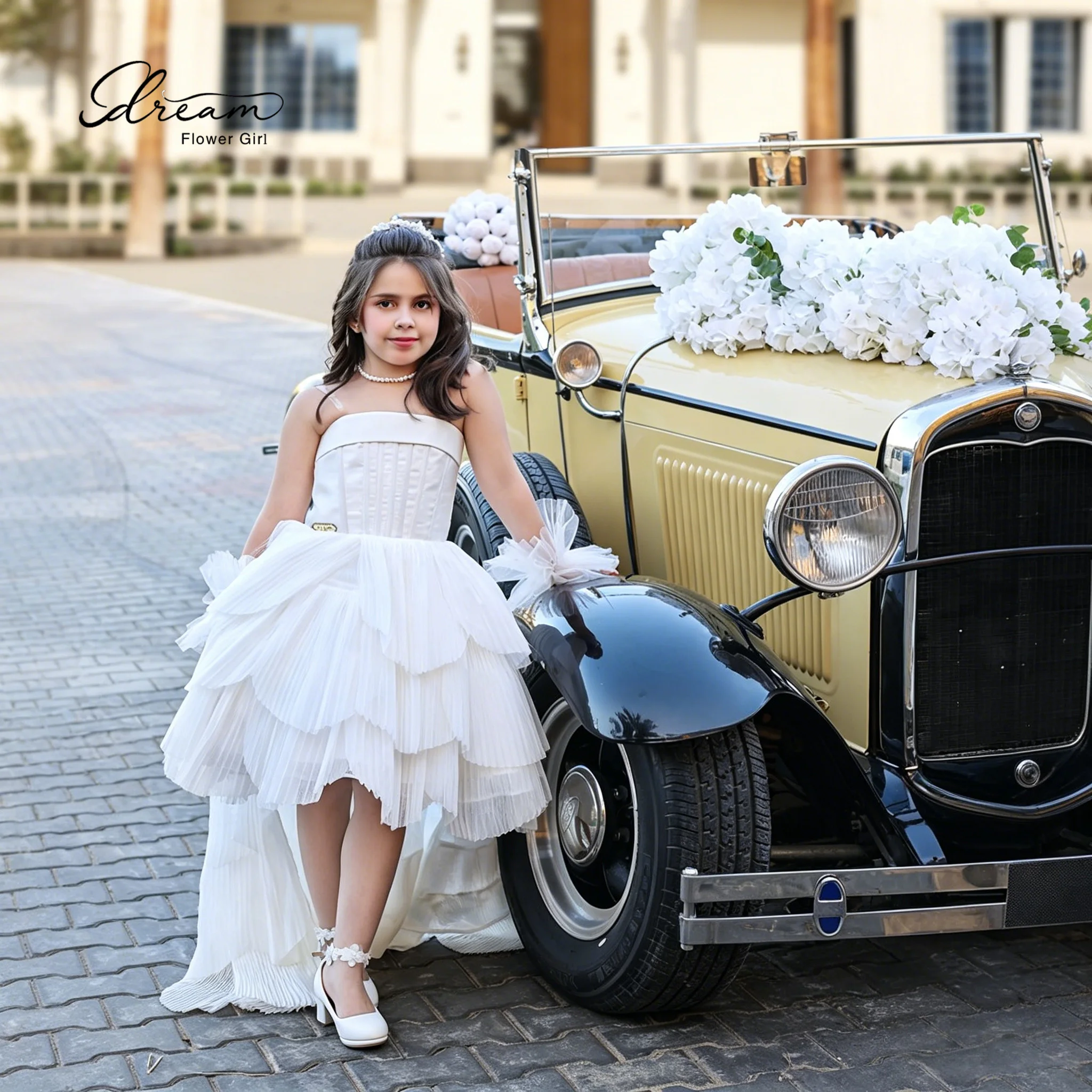 The elegant flower girl's strapless voluminous skirt and floor-length evening gown features an asymmetrical draping hem design.