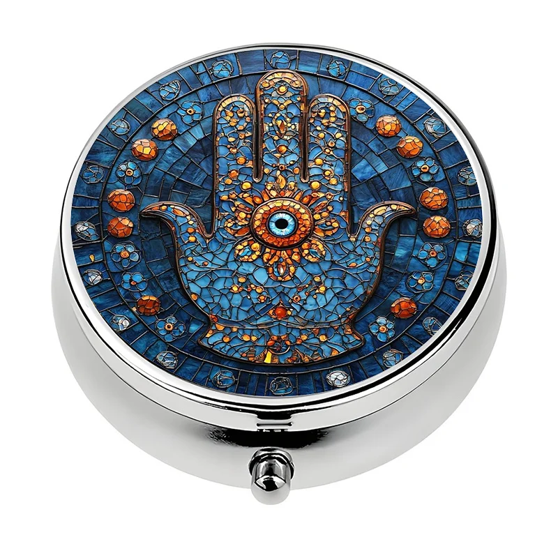 A portable pill box with a three-compartment design, featuring a hamsa hand and eye motif. This metal storage box is perfect for storing vitamins, making it a unique travel gift, and it easily fits into a wallet or bag.