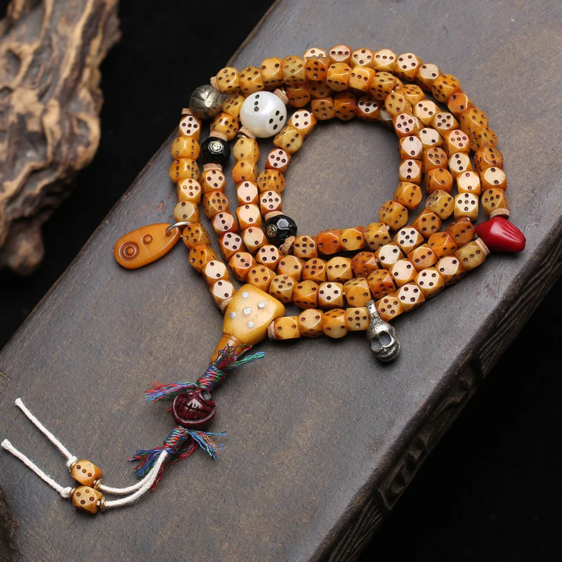 

Tibetan-style 108-bead prayer beads made from yak bone, carved dice, agate, copper tsa-tsa, and camel bone
