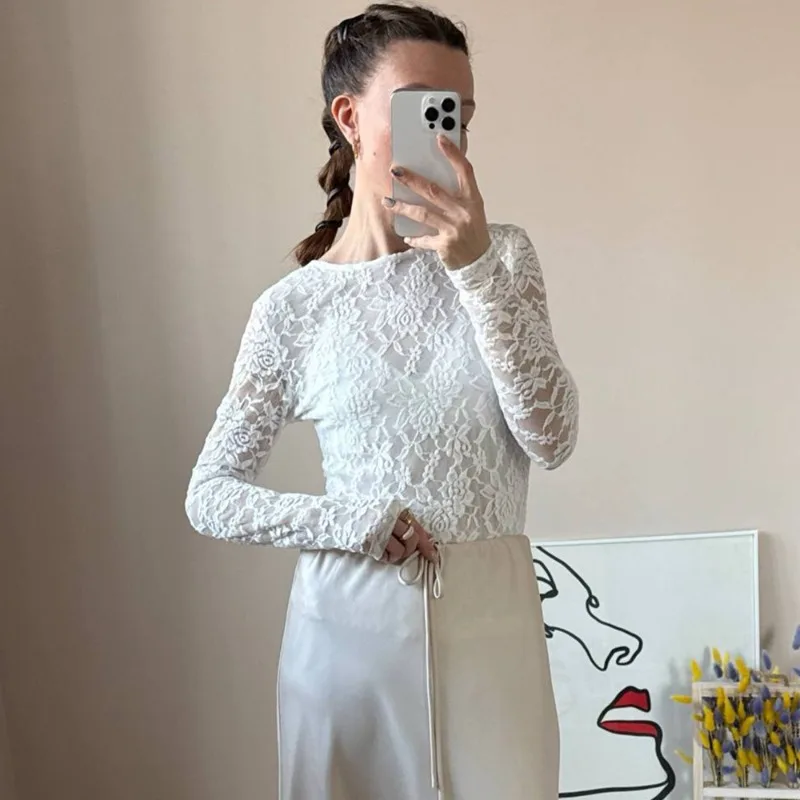 Blusa de encaje sexy de la marca Talenza, con mangas largas, diseño floral transparente, cuello barco y bajo asimétrico. Ideal para combinar en looks de primavera y verano.