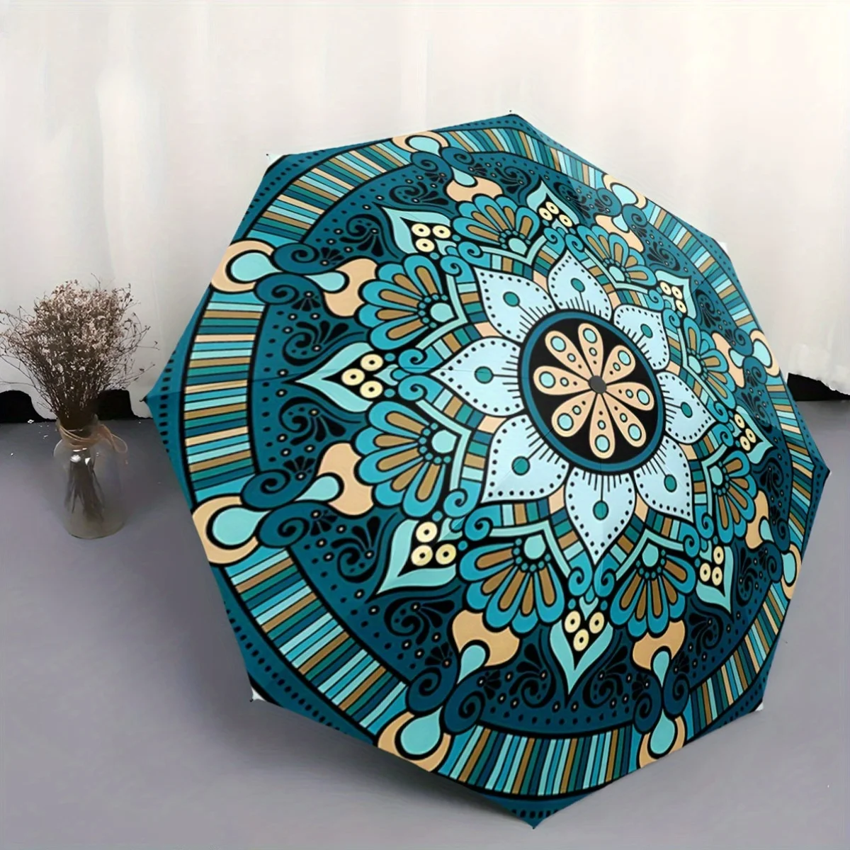 

Этот зонт имеет детализированный дизайн в виде мандалы в оттенках синего и бежевого. Это компактный, складной аксессуар, идеально подходящий для повседневного использования.