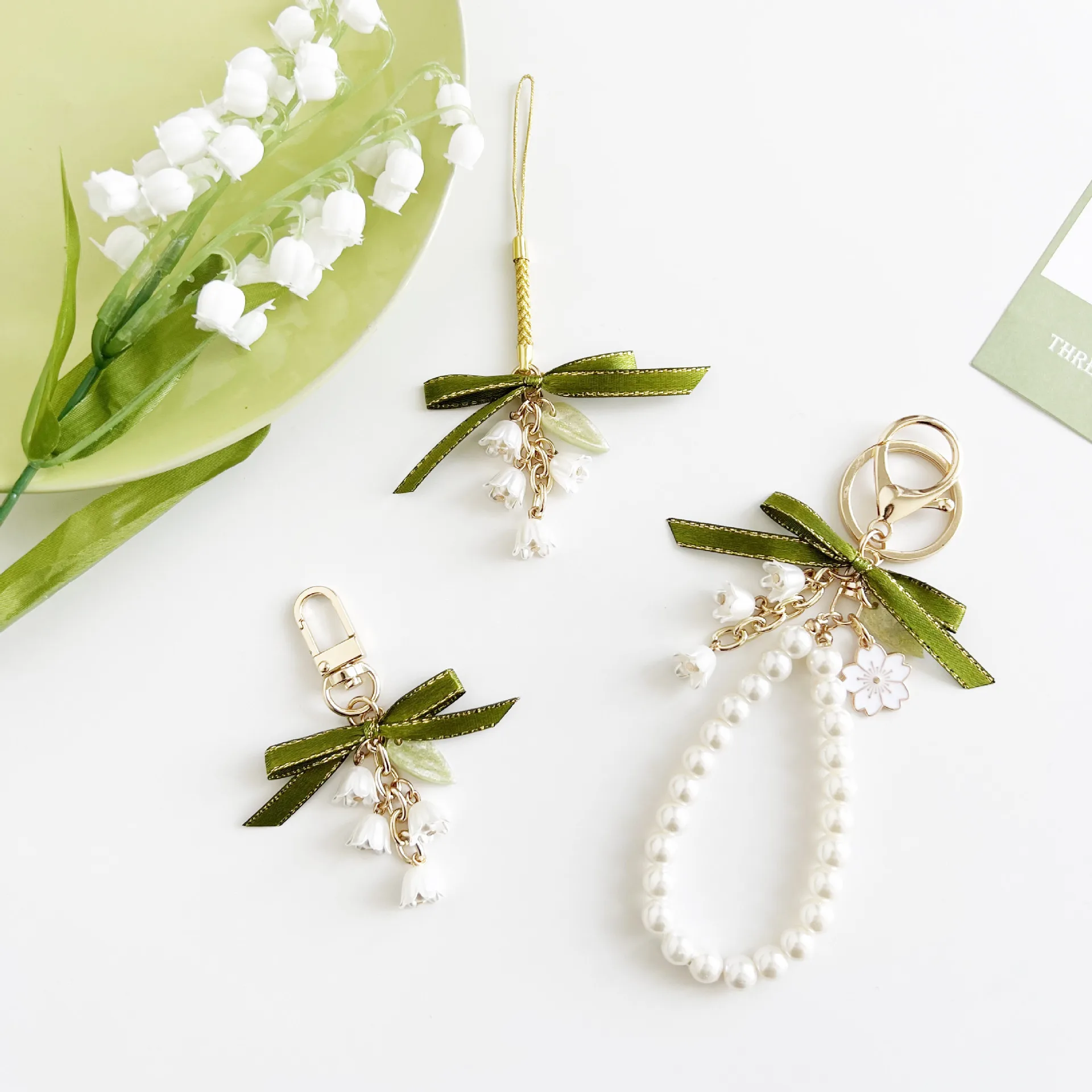 

Lily of the Valley Green Bowknot Pearl Wrist Rope AirPods Pendant Bag Charm Keychains Phone Chain for Women