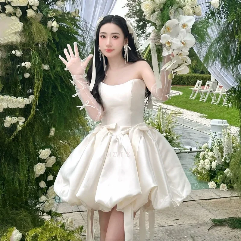 فستان زفاف قصير بسيط بيج بدون حمالات على شكل حرف a من الساتان بفيونكة قصيرة كورية لالتقاط الصور فستان زفاف مخصص للحفلات وأعياد الميلاد