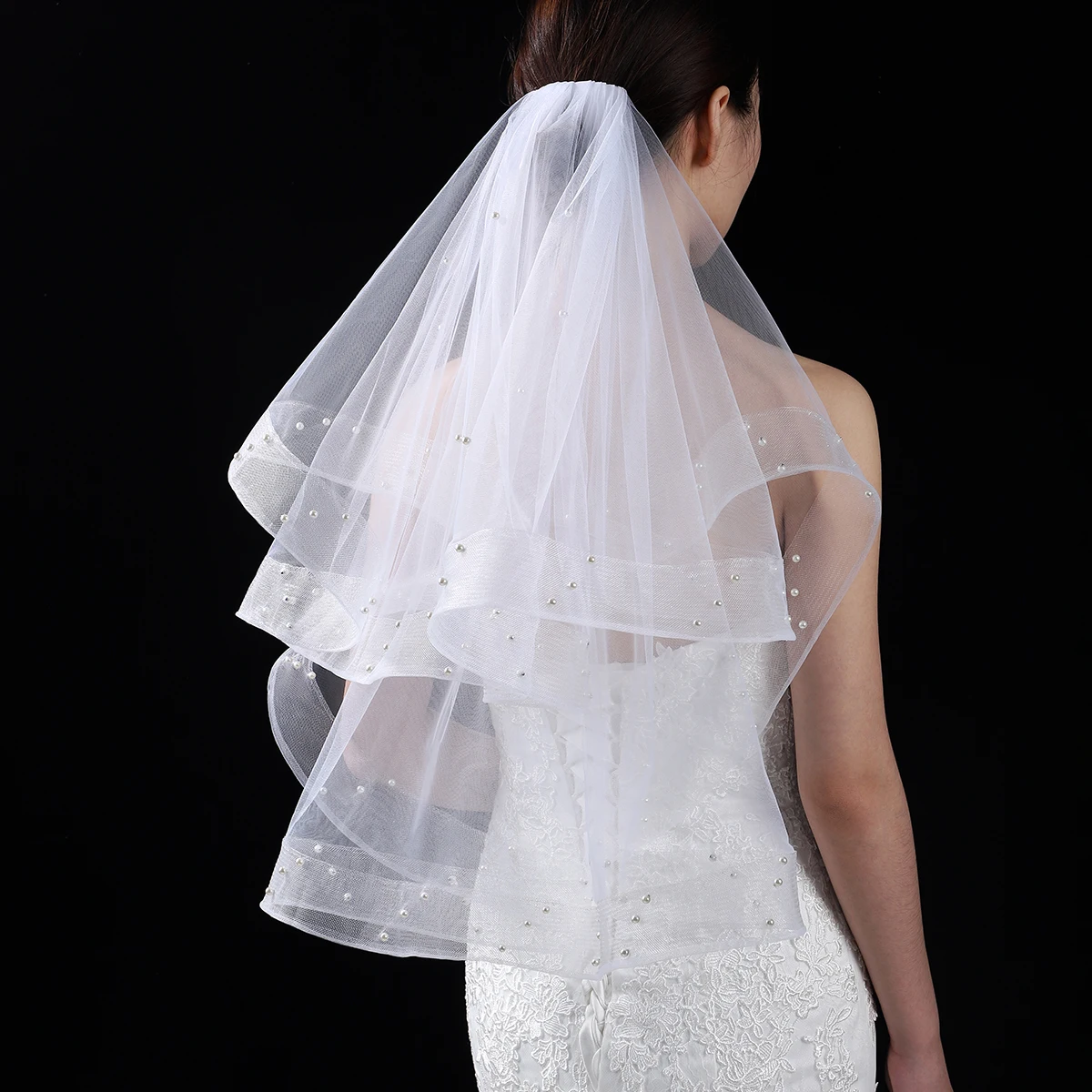 A white elegant bridal veil with a waist length veil adorned with simulated pearls, suitable for women's weddings