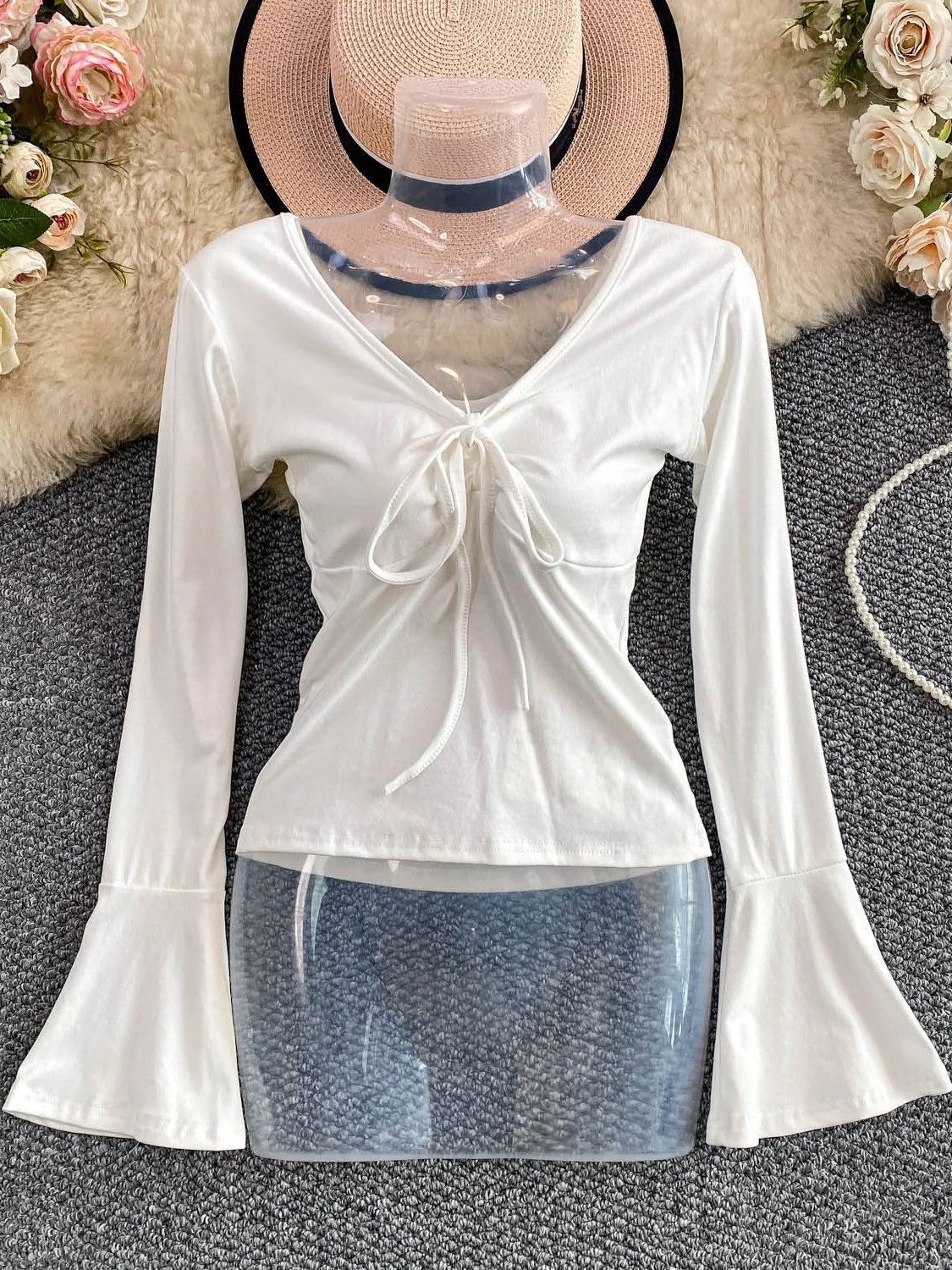 Seksowna, pikantna dziewczyna w dzianinowym, długim swetrze z dekoltem w serek, paskiem, wyszczuplającym krojem i dzwonkowymi rękawami, casualowy styl na jesień, moda damska.