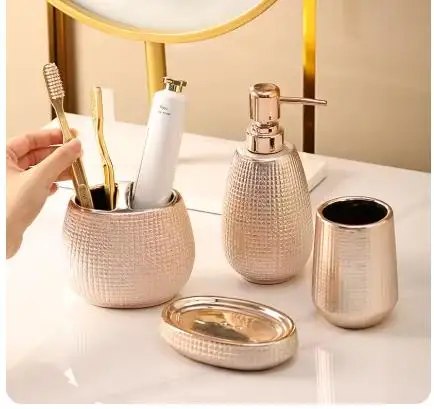 

Набор аксессуаров для ванной комнаты из розового золота: керамический флакон для лосьона, стакан для ополаскивателя, держатель для зубных щеток, флакон для шампуня и геля для душа, мыльница