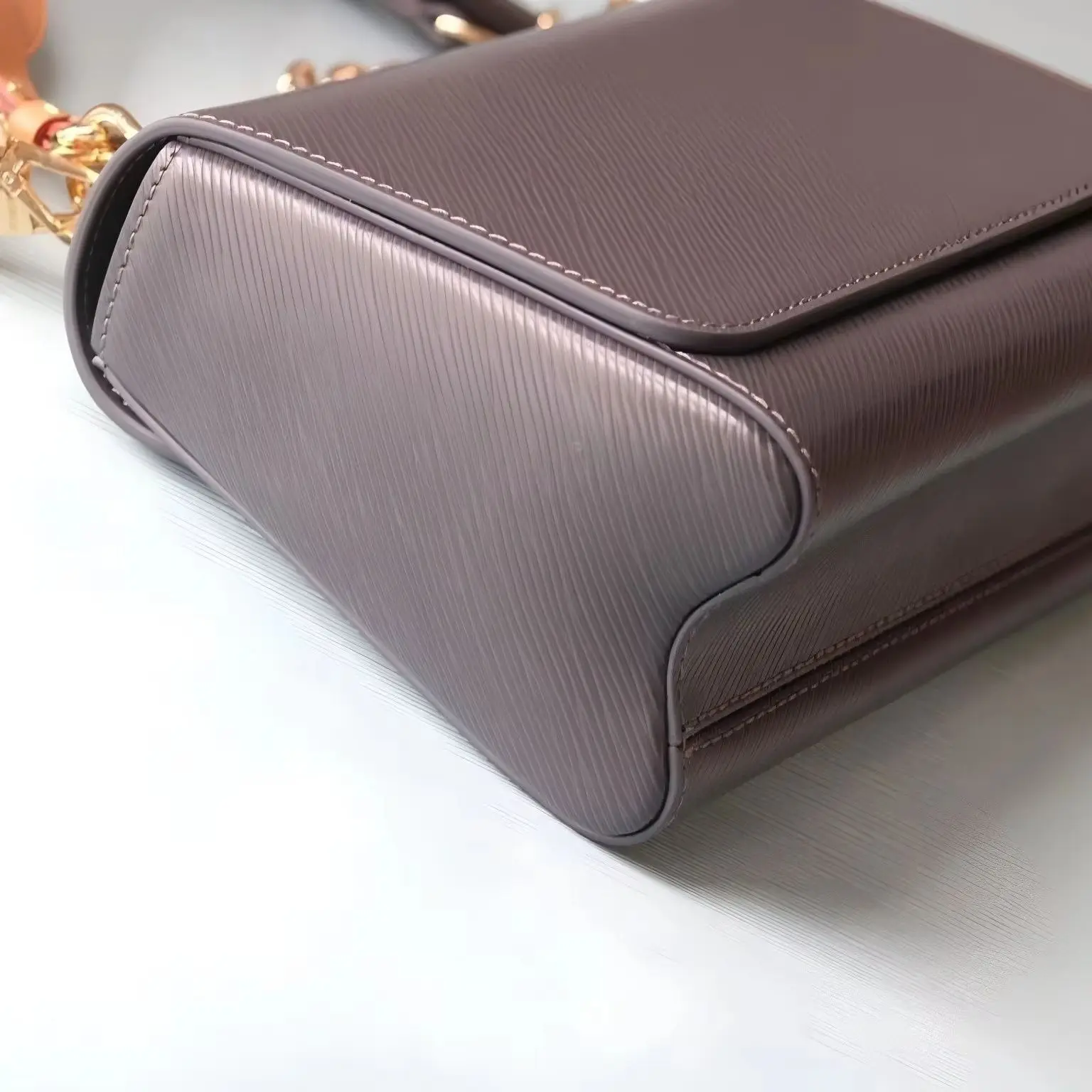 Textured water ripple leather shoulder bag with flap and metal lock, minimalist streamlined silhouette, stylish bag.