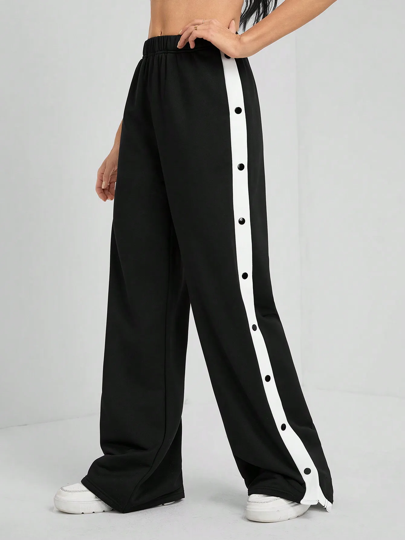 

Черные широкие брюки с белой боковой полосой и кнопками-застежками