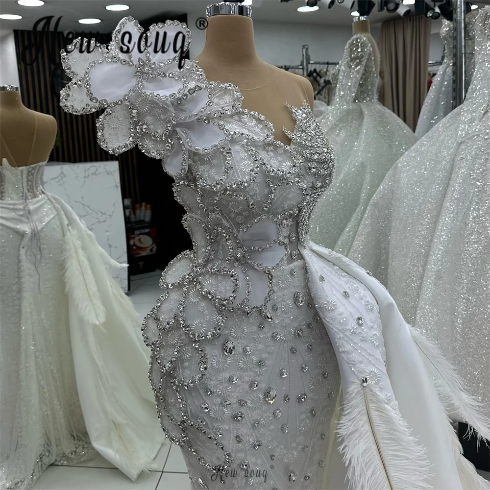 Luxuriöses weißes Feder-Hochzeitskleid mit Überrock, 2026, neue Dubai-Brautkleider, maßgeschneidertes One-Shoulder-Hochzeitskleid mit Kristallen und Spitze
