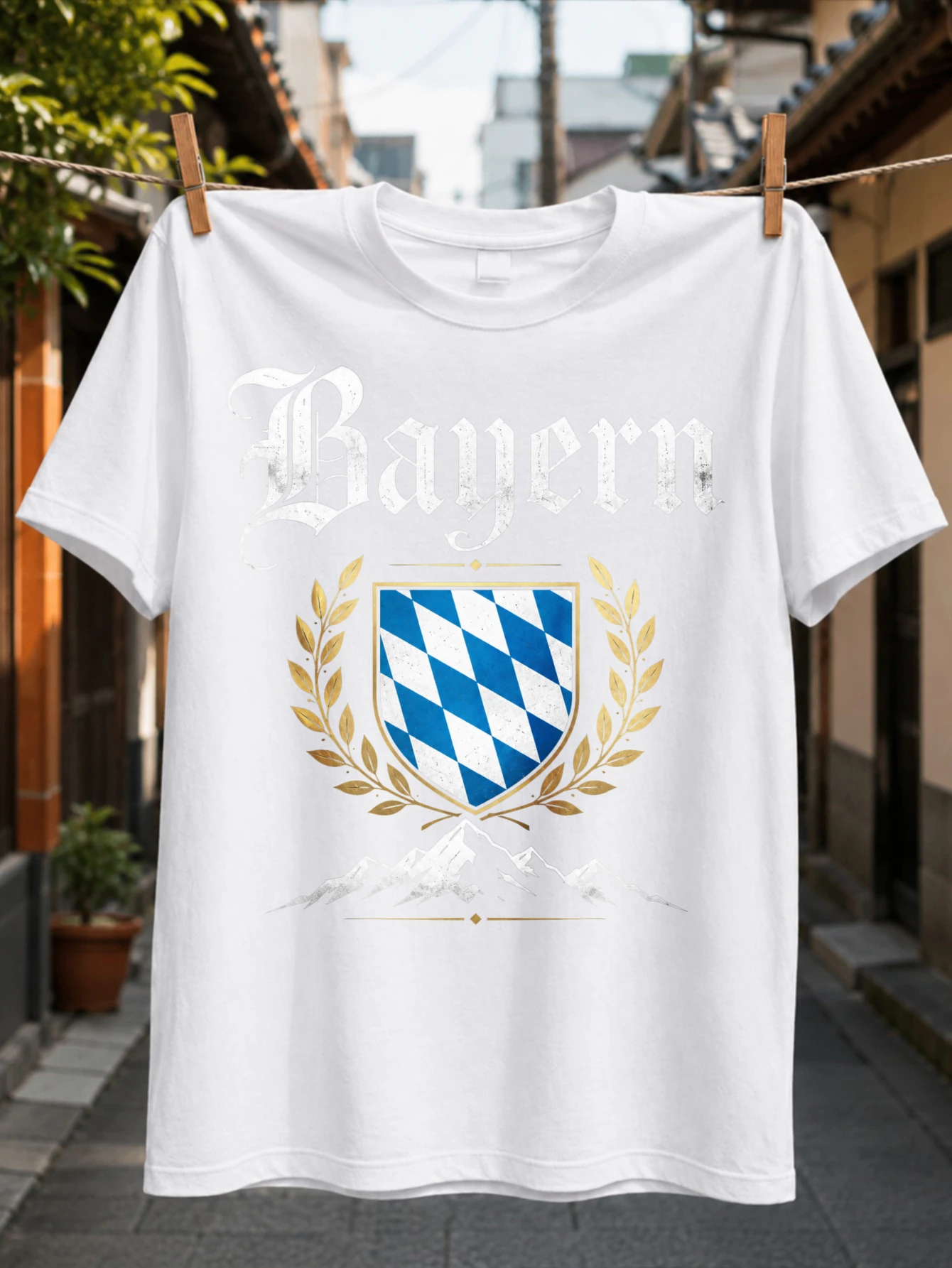 Design inspiré du patrimoine du Bayern avec un motif de laurier bleu doré et une silhouette de montagne sous des lettres gothiques T-shirt unisexe