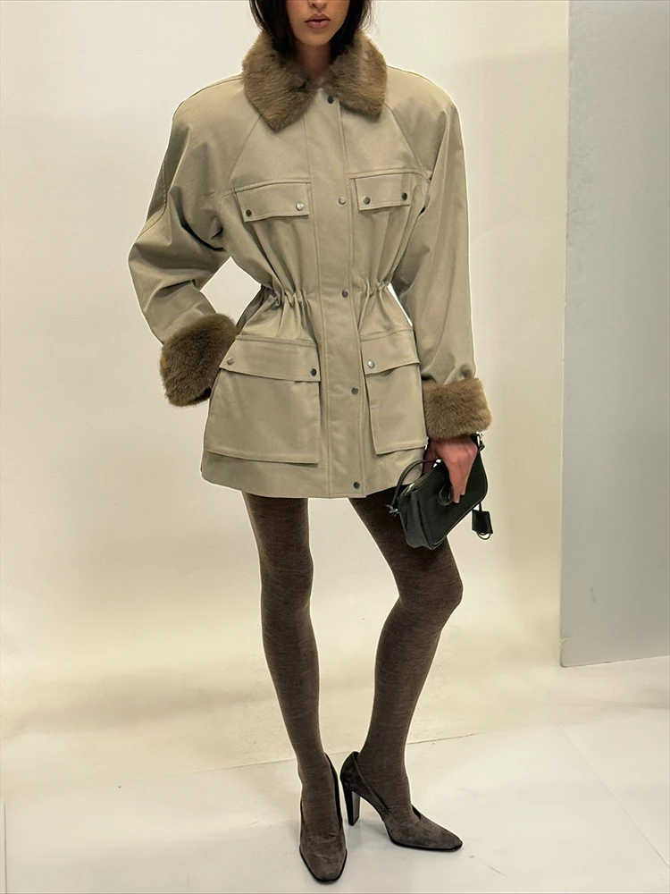 Damska kurtka średniej długości z futrzanym kołnierzem, wieloma kieszeniami i podkreśloną talią, w stylu odzieży roboczej.