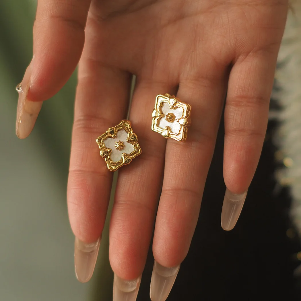 

Earrings and stud earrings with a brushed process, in a diamond-shaped clover design, made of white mother-of-pearl and featurin