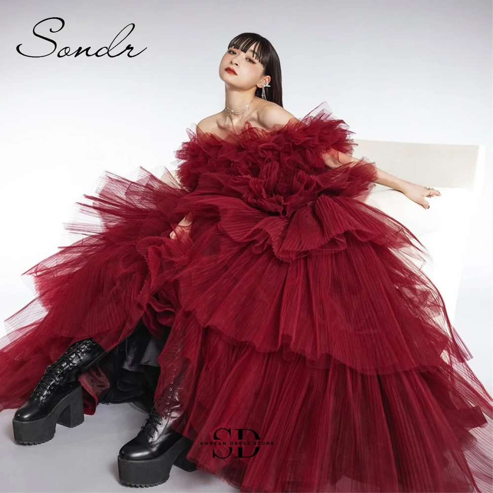 korean red wedding dress A photo of a Korean actress wearing a vibrant red embroidered ball-gown-style  wedding dress with sparkling sequins and beads creating a floral pattern.  The dress has a v-neckline, long sleeves with slight