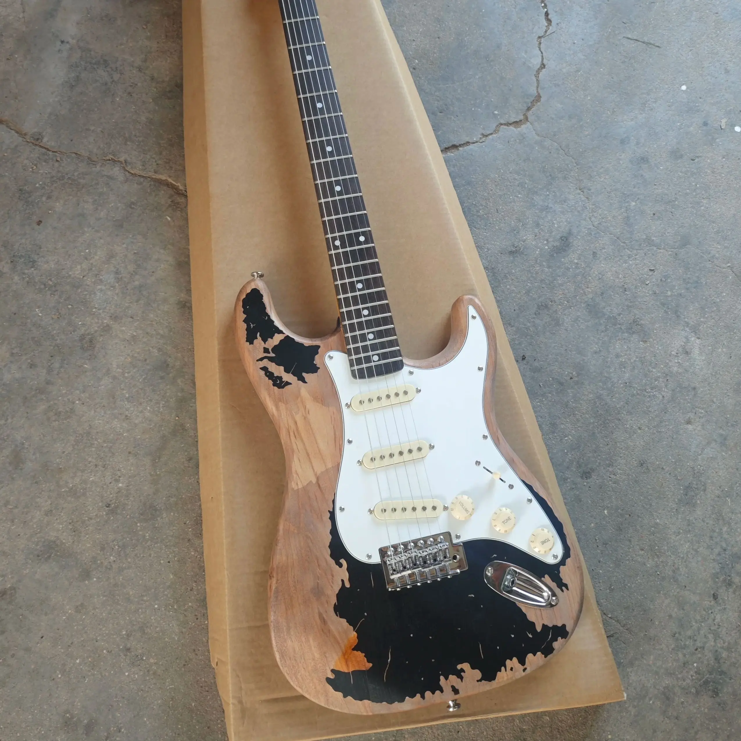 Black six string electric guitar with distressed treatment, featuring a basswood body, maple neck, and white panel