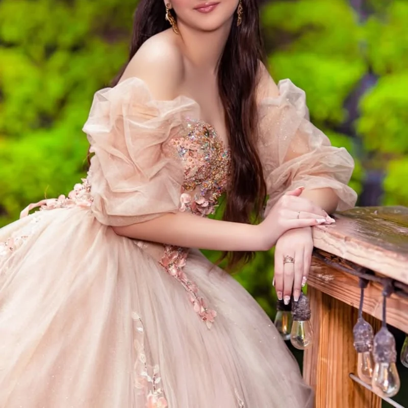 ชุดเดรสงาน Quinceanera สีแชมเปญอ่อน ประดับคริสตัลวิบวับ ลายดอกไม้ 3 มิติ พร้อมชายกระโปรงยาว ﻿ ปรับแต่ง