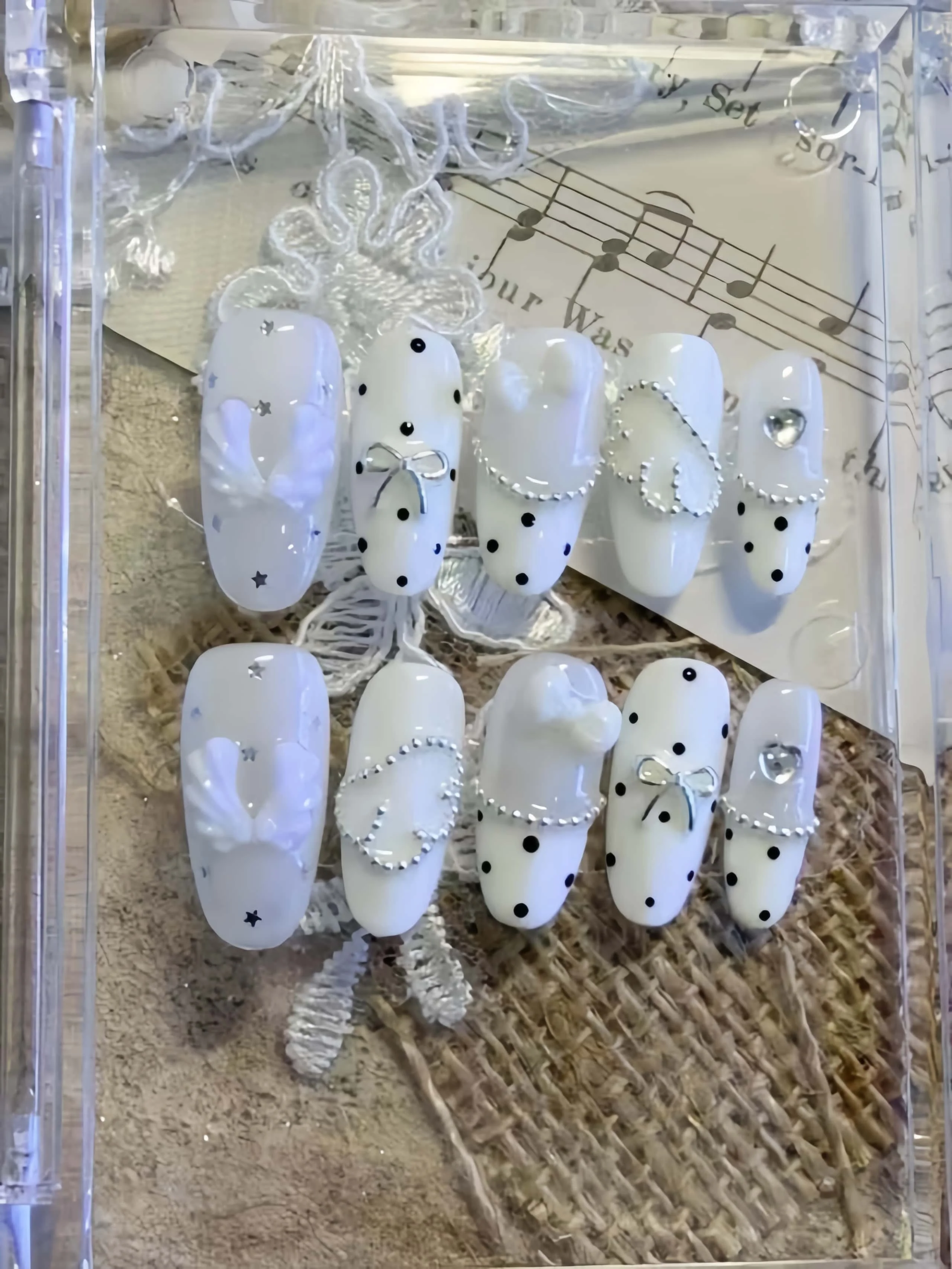 10 Pieces of Handmade Oval Full-Cover Nail Tips, Medium Length, with a Clear Milky White Base Color Paired with Small Black Polka Dots, 3D White Wings, Silver Bow, and Chain Heart Rhinestones, in a Fresh Korean Sweet-Cool Style, Suitable for Women and Girls, Perfect for Summer Vacations, Graduation Season, and as a Gift, Comes with 1 Piece of Jelly Glue and 1 Nail File