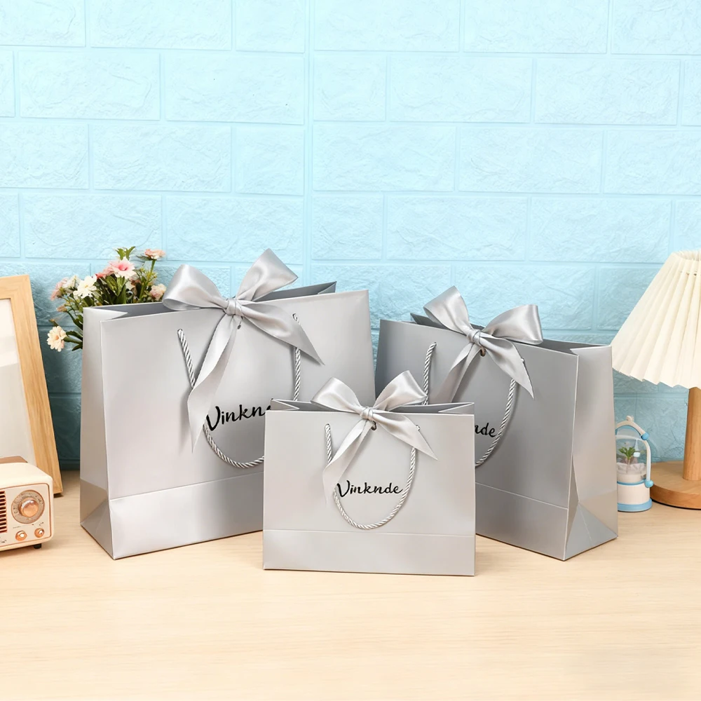 

Роскошный серебристо-серый подарочный бумажный пакет с индивидуальным принтом логотипа для обуви, одежды, покупок, свадебный подарок, упаковка ювелирных изделий с бантом, лентой