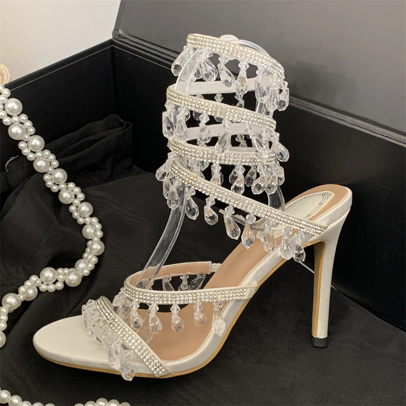 Eilyken Neue Mode Kristall-Diamant-Anhänger Damen-Sandalen Elegante Sexy Dünne Hohe Absätze Knöchelriemen Bankett-Karnevalsschuhe