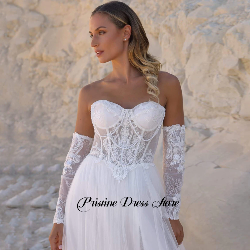 Suknia ślubna w stylu boho z odpinanymi rękawami, tiulowa, z rozcięciem z boku, sznurowana na plecach, dekolt w serce, zdobiona perłami, fason A-line, możliwość personalizacji.