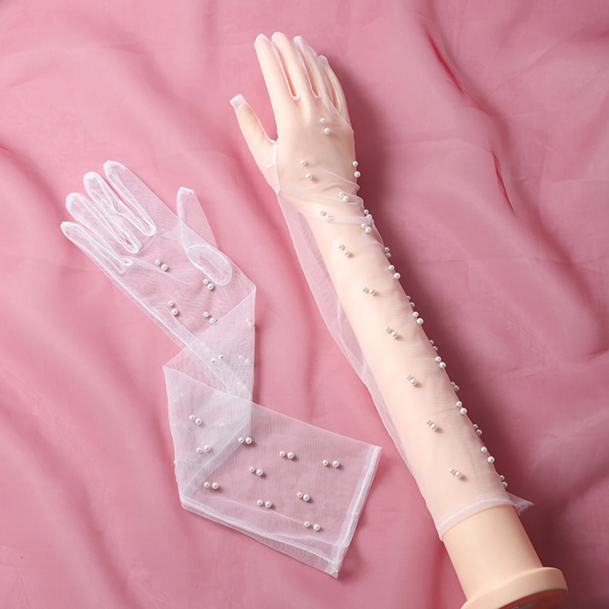 A pair of transparent fingered style elbow length gloves suitable as accessories for bride weddings or women's dances