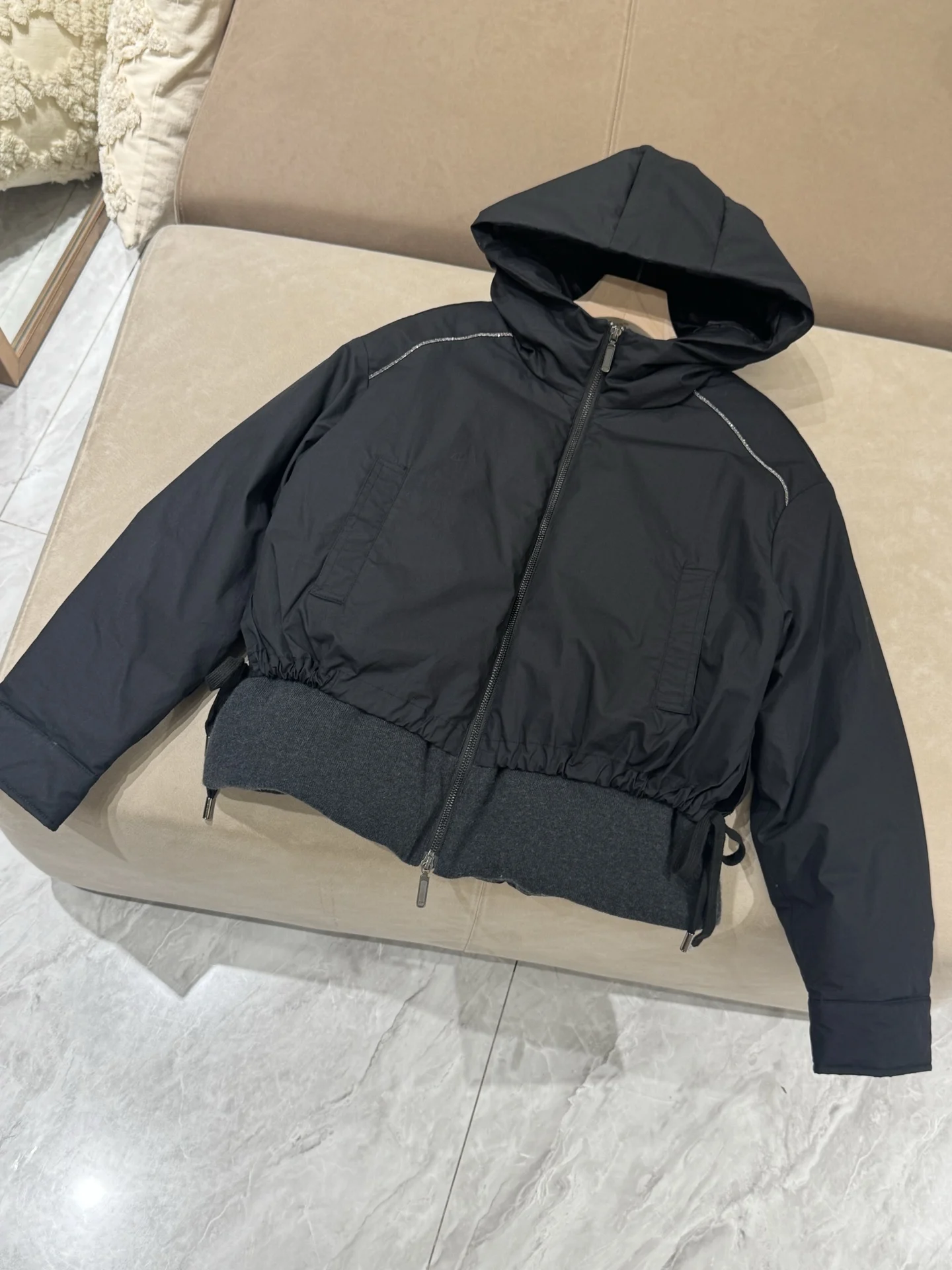 เสื้อแจ็คเก็ตขนเป็ดผสมแคชเมียร์ ขนสัตว์ และผ้าไหม พร้อมฮู้ด แต่งโซ่ประดับลูกปัด และแขนเสื้อแบบดรอปชอลเดอร์ เพื่อทรงสวยสง่า