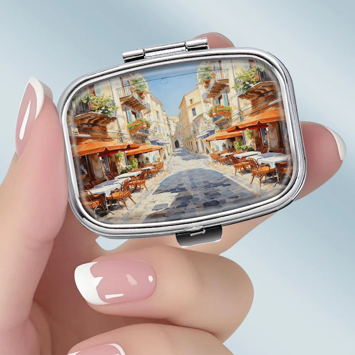 1PC A portable square metal pill box featuring a bright and relaxed scene of a southern European small town street, with a 2-compartment design, perfect for elegantly storing your medication or supplements. It is very suitable for sorting vitamins and sto