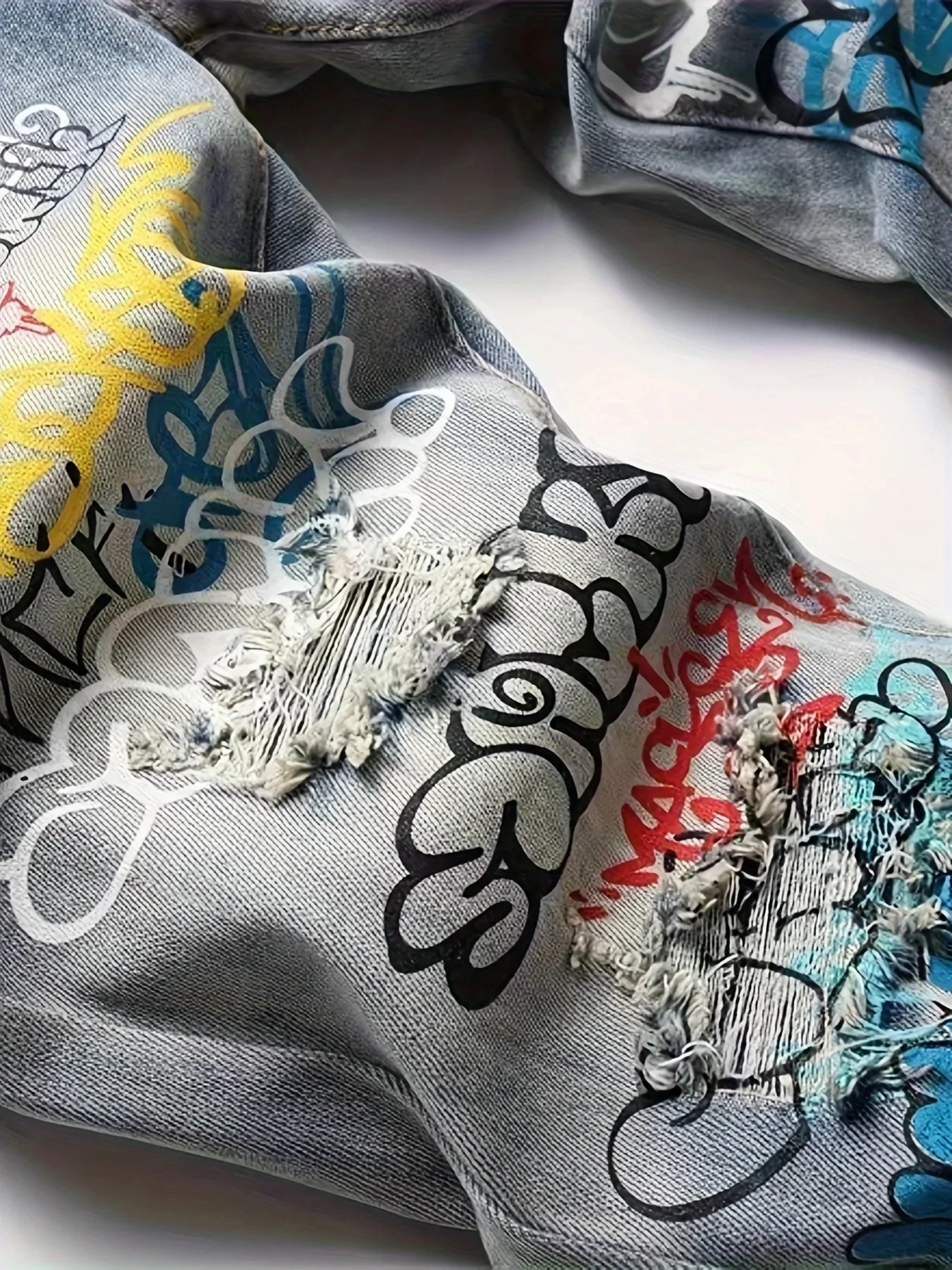 Vecchi jeans lavati e strappati con graffiti stampati europei e americani