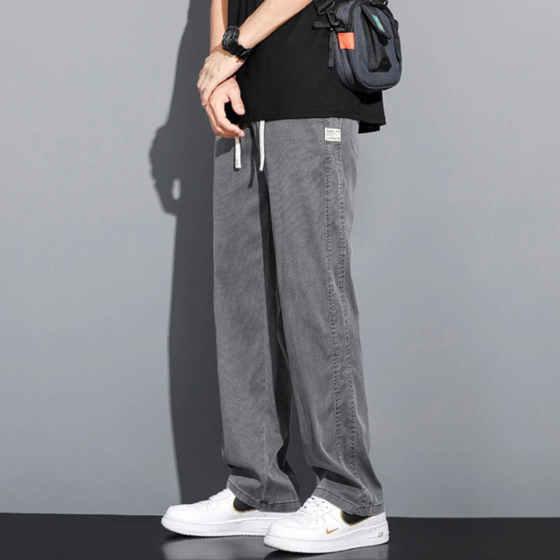 Celana jeans pria musim panas, model longgar potongan lurus, pinggang elastis dengan tali serut, gaya kasual Korea, ukuran besar M-5XL