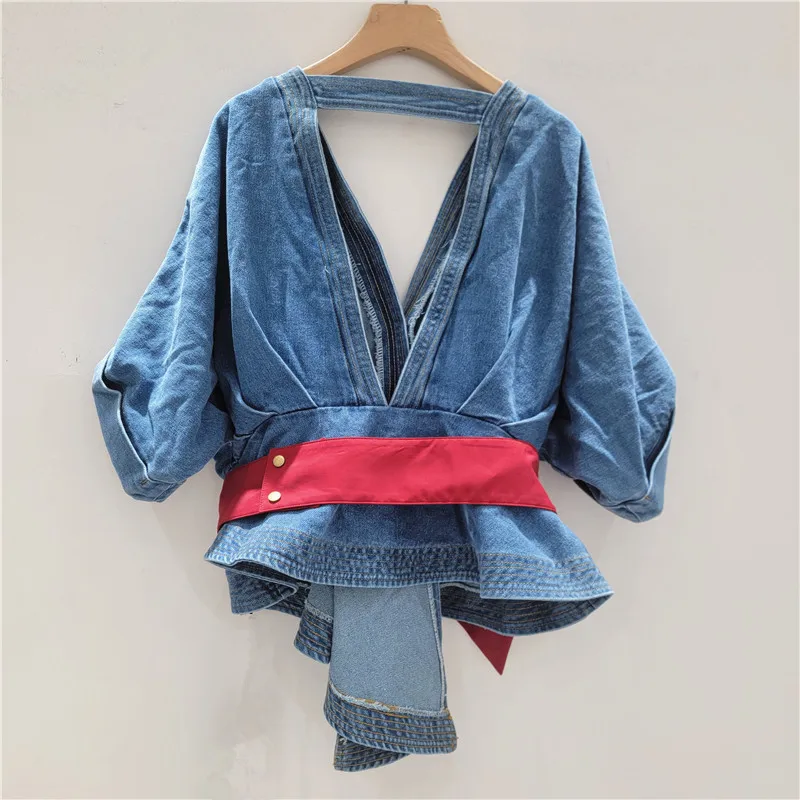 

French Chic Edge. This denim shirt features a contrast bow, waist-defining cut, and a daring backless design for 2025.