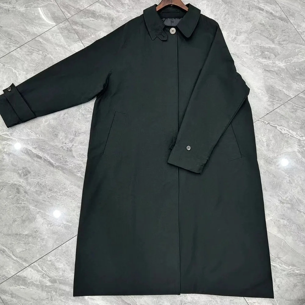 Jesienny płaszcz wiatrówka o klasycznym kroju, z wysokim rozcięciem, wykonany z mieszanki bawełny, o kroju litery A, średniej długości, zapinany na wiele guzików.