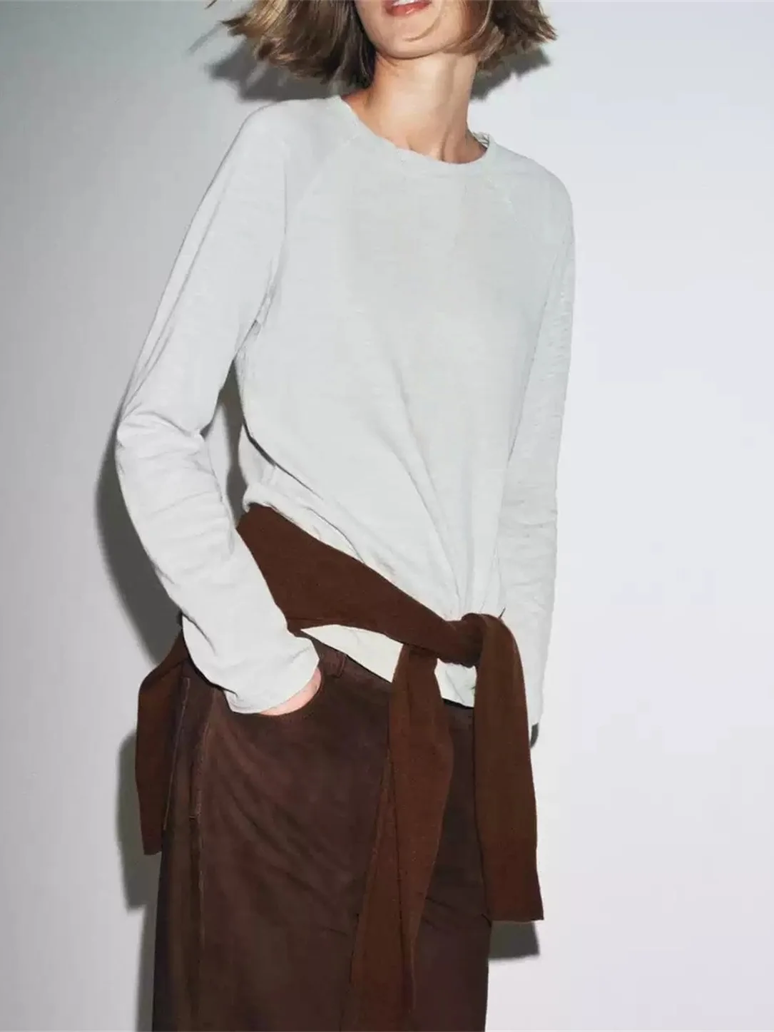 قميص نسائي جديد للخريف بتصميم بسيط وأنيق، مصنوع من القطن بأكمام طويلة وياقة مستديرة، مع تصميم مميز عند الكتف، مريح وعصري