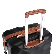Close-up of luggage handle with brown grip attached to black suitcase. Extendable metal handle visible.