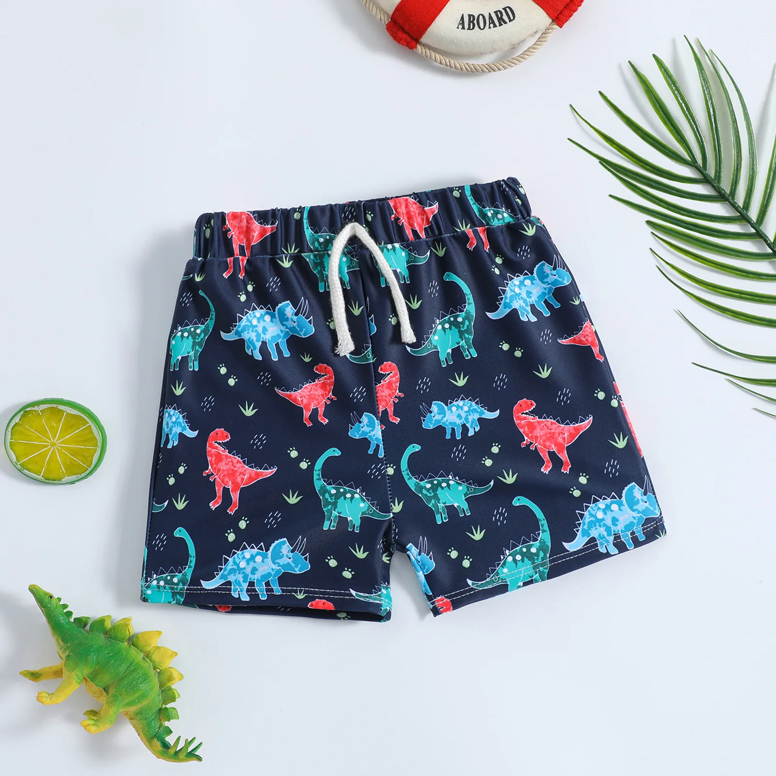 Boys drawstring swim shorts with full colorful dinosaur print on dark blue base suitable for seaside vacation and pool water pla