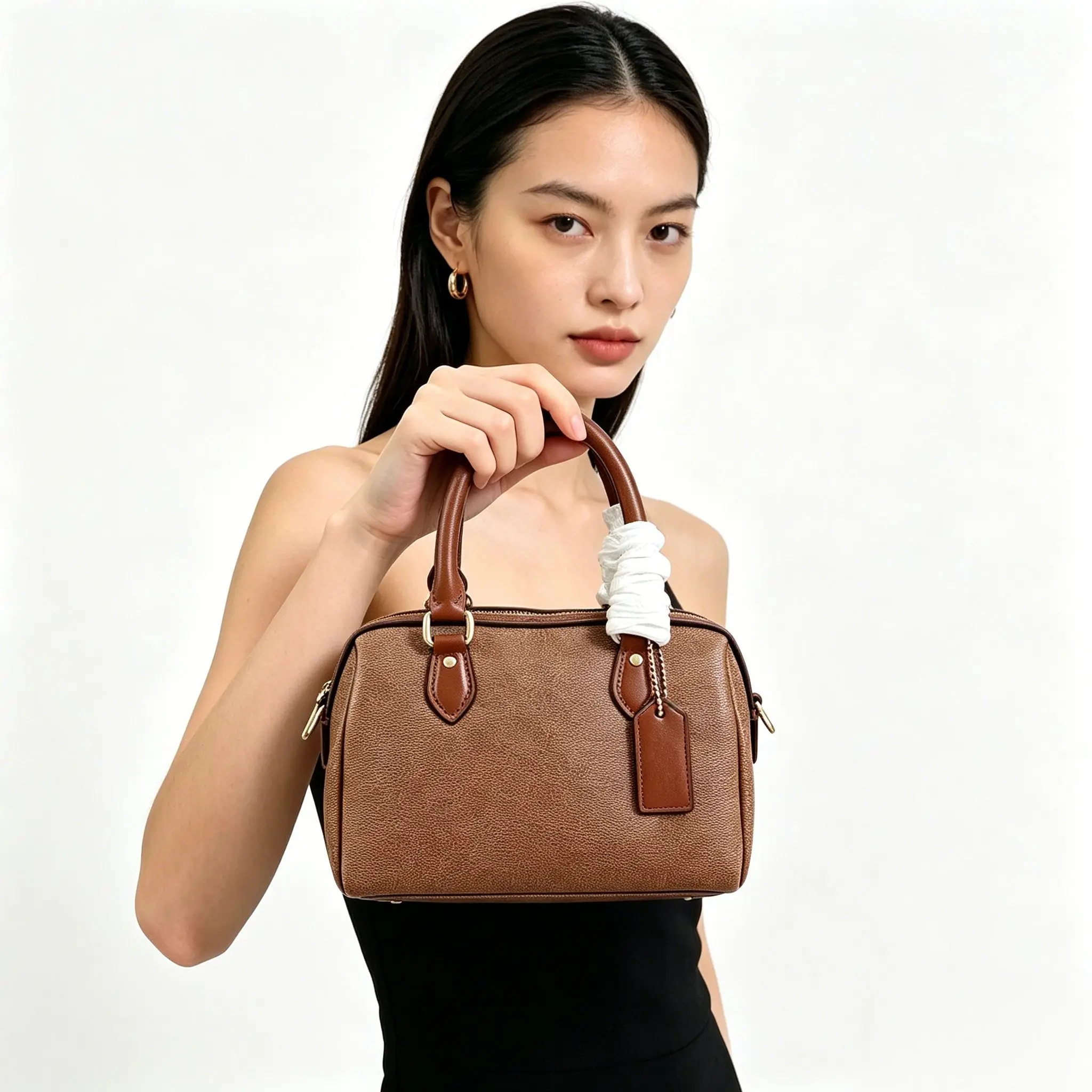 

Mini brown two-tone leather barrel bag with top handles, gold-tone hardware, and a detachable luggage tag.