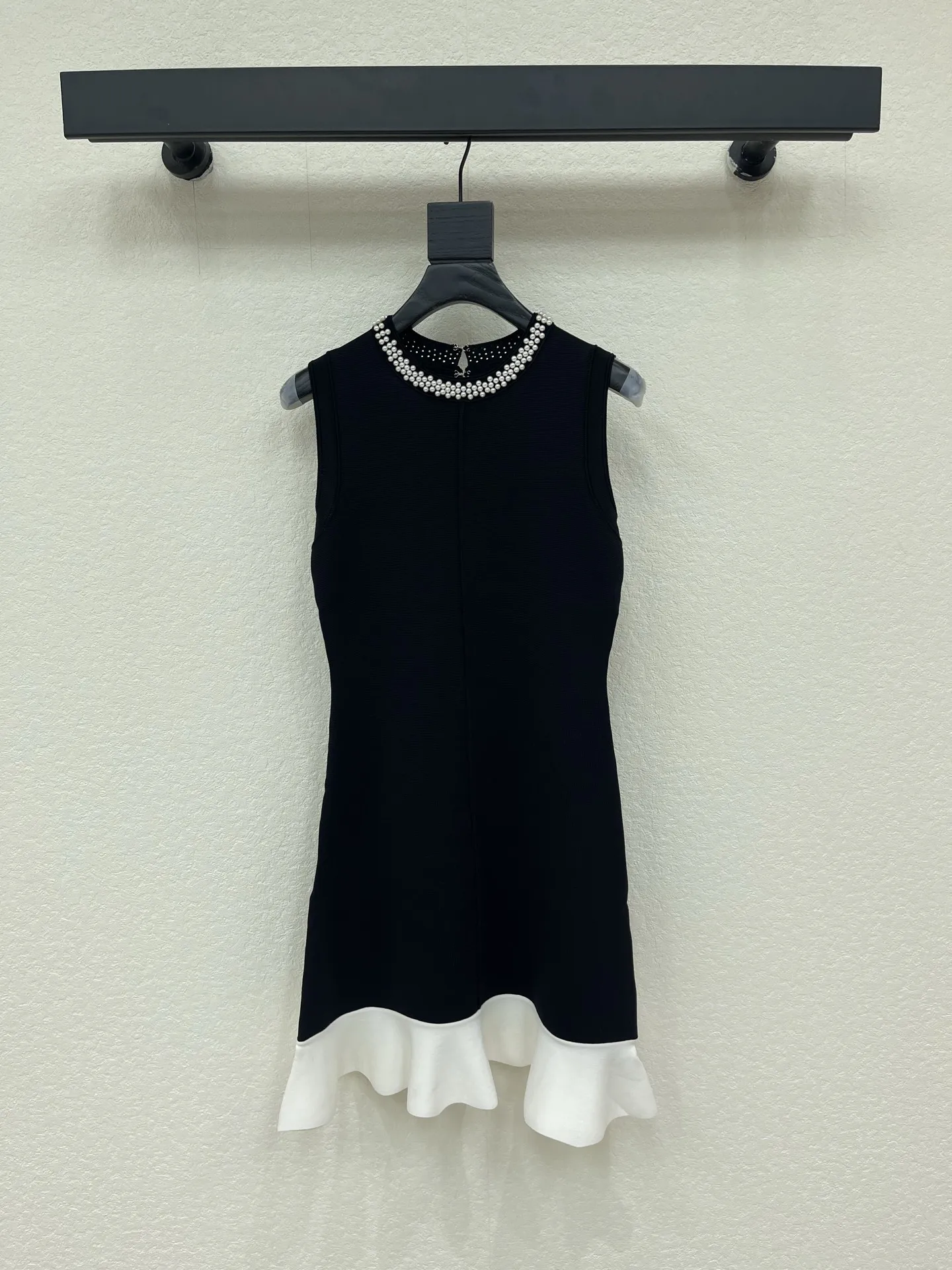 Black pearl round neck sleeveless knitted dress with contrasting white border and lotus leaf fish tail hem, slimming short dress
