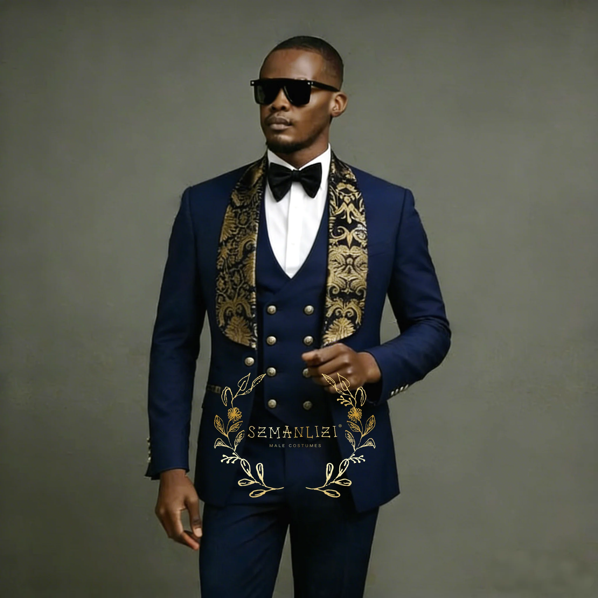 

Мужской костюм-тройка темно-синего цвета: приталенный смокинг для свадьбы с золотистым цветочным узором на шаль-воротнике, жакет, жилет и брюки. Модель 2026.