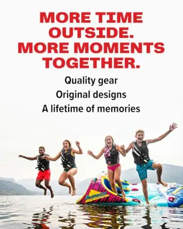 Four kids in life jackets jumping off an inflatable water float into a lake together.