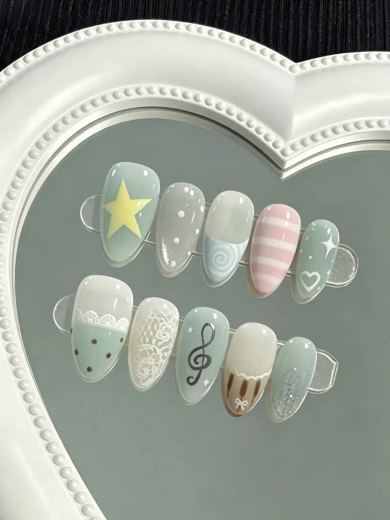 10 pieces of handmade almond-shaped full-cover nail tips, medium-long in length, with a mint green and milky white color combination, featuring hand-painted designs of stars, music notes, lace, and stripes, in a fresh Korean sweet girl style, suitable for women and girls, ideal for summer vacations and graduation season, suitable as a gift, comes with 1 piece of jelly glue and 1 nail file